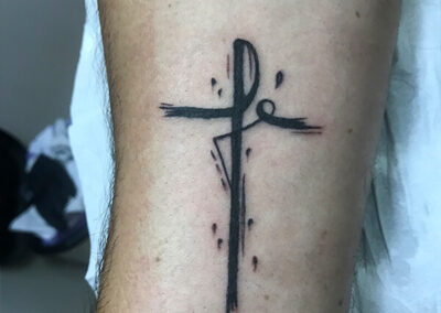 Tatto de la palabrá "fé" formando una cruz