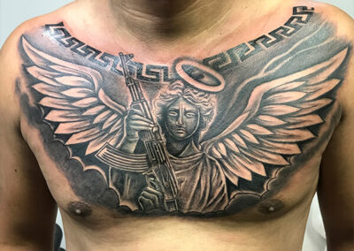 Tattoo en el pecho de un ángel con Kalasnikov